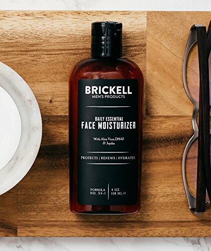 Brickell face moisturizer bottle on wooden surface with glasses