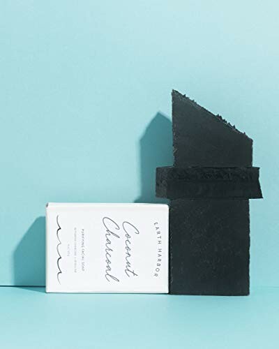 Coconut charcoal soap with packaging on blue background.