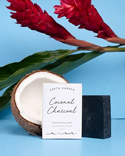 Coconut charcoal soap with coconut and red flowers on blue background.