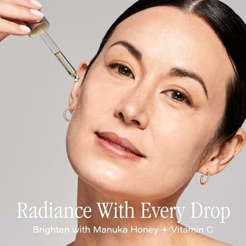 Woman applying skincare serum with dropper.
